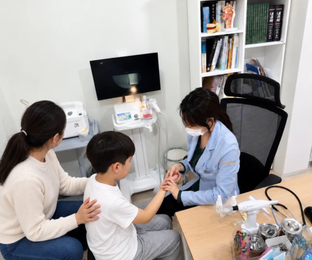 아이조아한의원 동탄 진료실에서 원장이 아이의 손을 잡고 진찰하며 보호자에게 설명하는 모습
